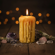 Candle with wicks on a wooden surface with lavender, crystals, and blurred lights in the background.