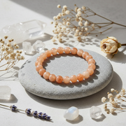 Orange bracelet on a stone surrounded by crystals and flowers.