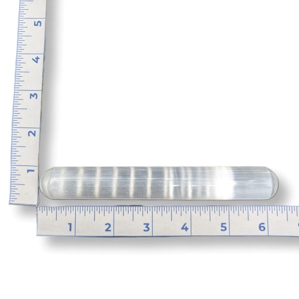 A selenite wand with measurement scale on a white background