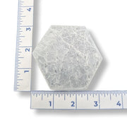 Hexagonal selenite plate with a ruler for scale on a white background