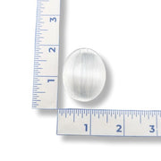 White Selenite worry stone next to a ruler on a white background