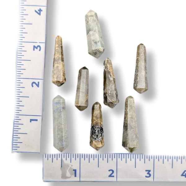 Several small natural labradorite  points arranged on a white background with ruler markings along the left and bottom edges for size reference.