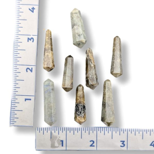 Several small natural labradorite  points arranged on a white background with ruler markings along the left and bottom edges for size reference.