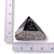 Pyramid-shaped stone next to a ruler on a white background