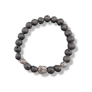 A beaded stretch bracelet made of dark gray porous lava stones, featuring a central silver owl charm and two textured silver spacer beads, shown on a white background.