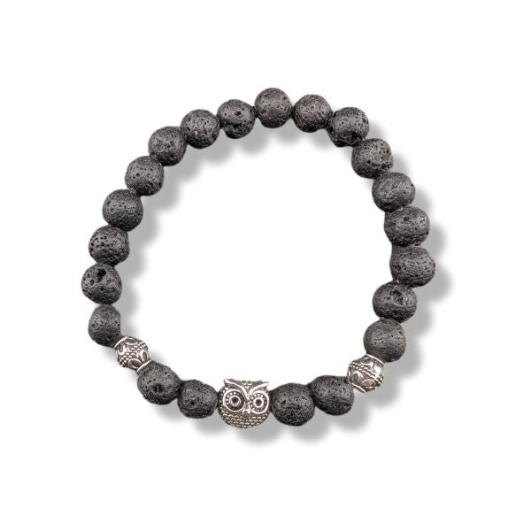 A beaded stretch bracelet made of dark gray porous lava stones, featuring a central silver owl charm and two textured silver spacer beads, shown on a white background.
