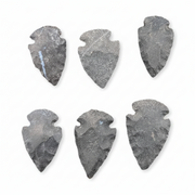 Six dark gray stone arrowhead tools arranged in two rows on a plain white background.