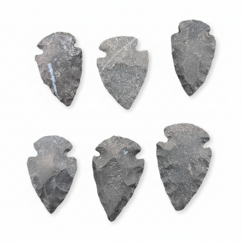 Six dark gray stone arrowhead tools arranged in two rows on a plain white background.