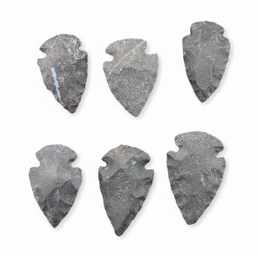 Six dark gray stone arrowhead tools arranged in two rows on a plain white background.