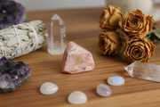 Mineral specimen, crystals, and dried roses on a wooden surface
