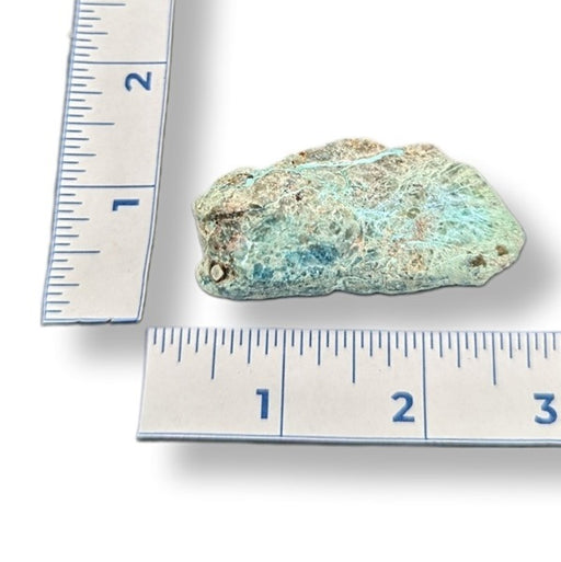 Mineral sample with a ruler showing its size on a white background