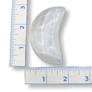 White selenite moon next to a ruler on a white background