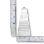 Selenite Obelisk Square Base with a ruler showing its length on a white background