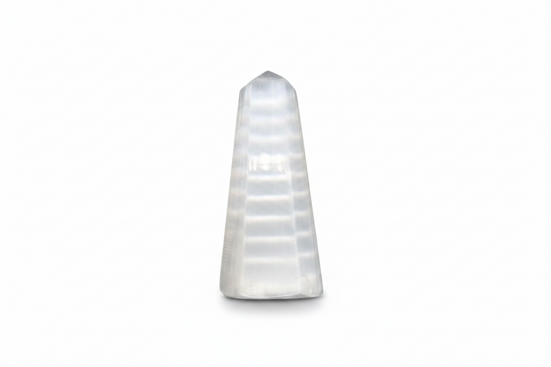 Selenite obelisk with horizontal striations, photographed against a seamless white background.