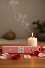 Candle with smoke, Champa box, and rose petals on a wooden surface