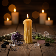 Candle with wick lit on a wooden surface with lavender, stones, and other items.
