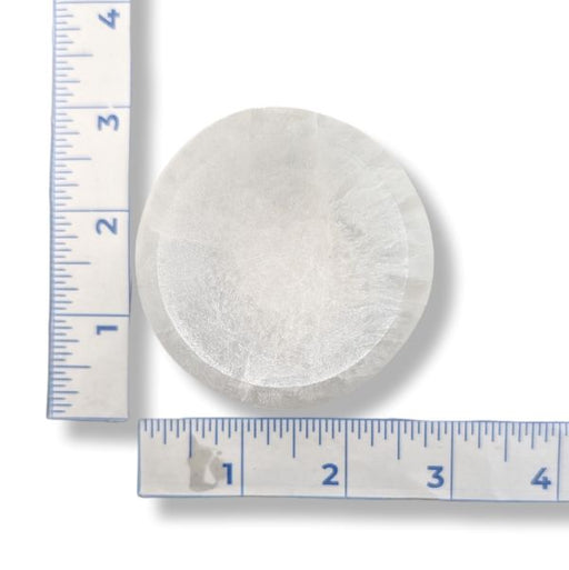 A round, Selenite 6cm bowl, next to two blue-and-white rulers for scale on a white background.
