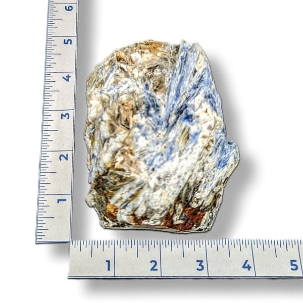 Mineral sample with blue streaks next to a ruler on a white background