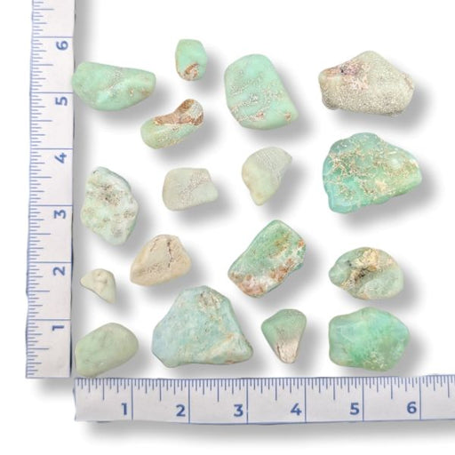 Chrysoprase stones with a ruler for scale on a white background