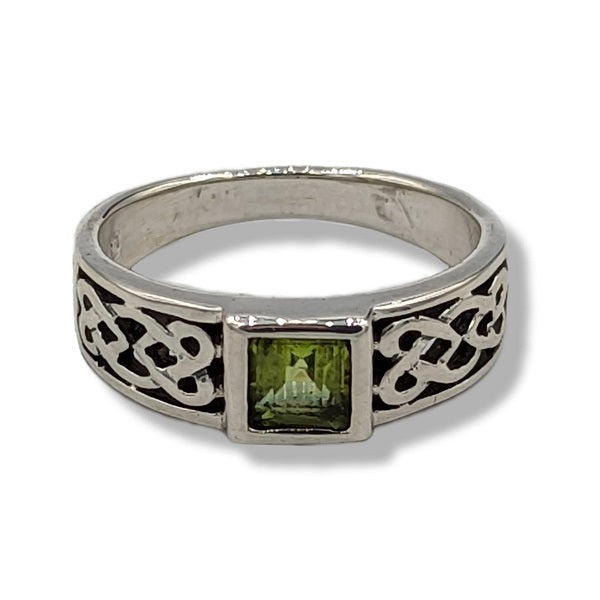 Silver ring with green gemstone and Celtic knot design on a white background