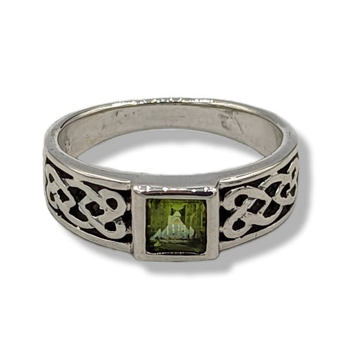 Silver ring with green gemstone and Celtic knot design on a white background