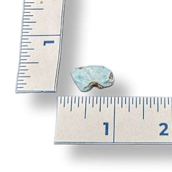 Larimar stone next to a ruler on a white background