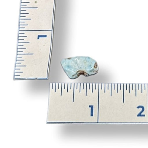 Larimar stone next to a ruler on a white background