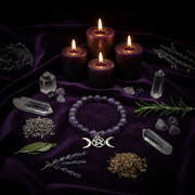 Wiccan or pagan altar setup with candles, crystals, and a bracelet on a purple cloth.
