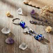 Keychain with elephant and eye design on a wooden surface with crystals and flowers