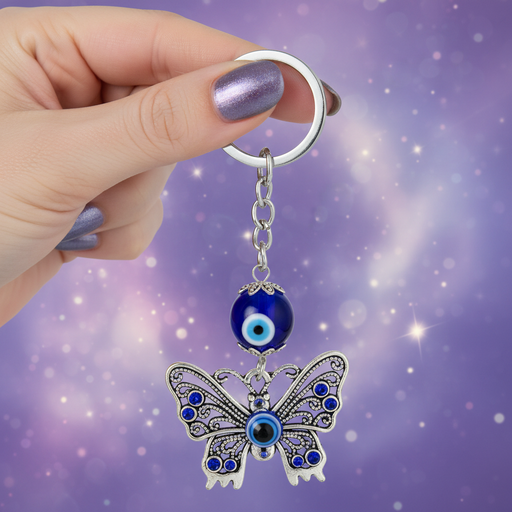 Butterfly keychain with blue evil eye charm held by a hand against a purple background