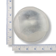 Round stone next to a ruler on a white background