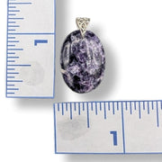 Purple stone pendant with silver bail on a white background with rulers for scale.