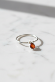 Silver ring with a orange gemstone on a white marble surface
