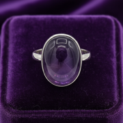 Silver ring with a purple gemstone on a purple velvet background