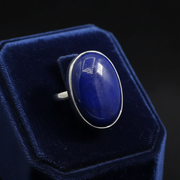Ring with a large blue stone and silver band on a blue riser.