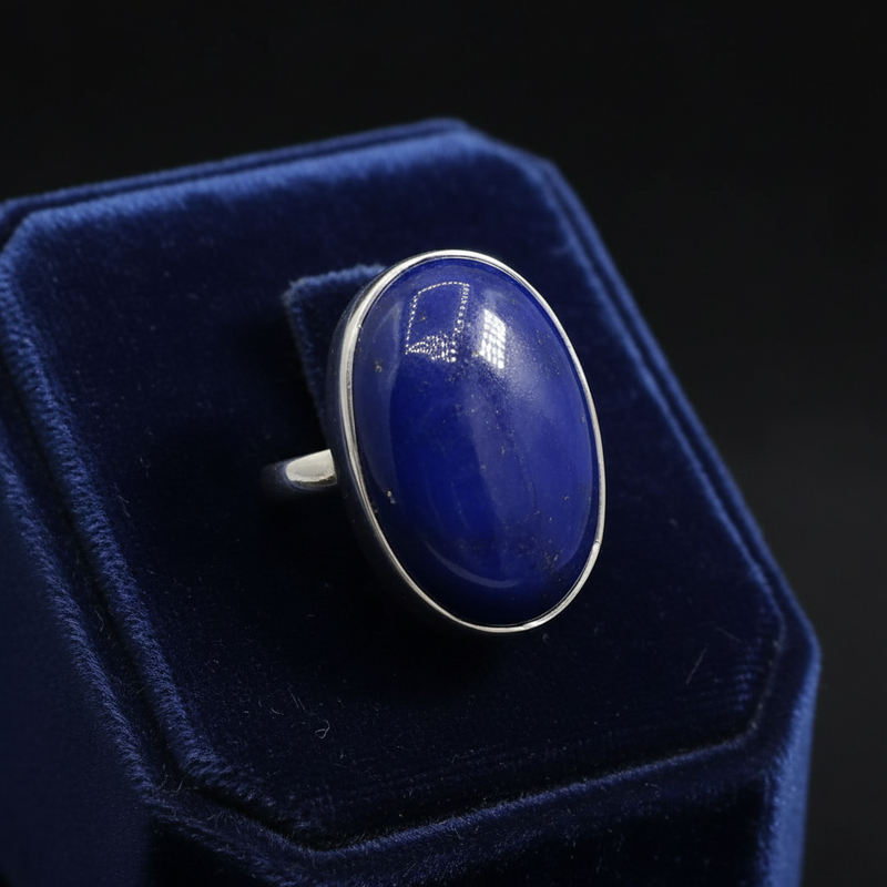 Ring with a large blue stone and silver band on a blue riser.