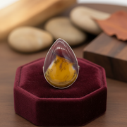 Teardrop-shaped Mookaite stone sterling silver ring on a burgundy riser.
