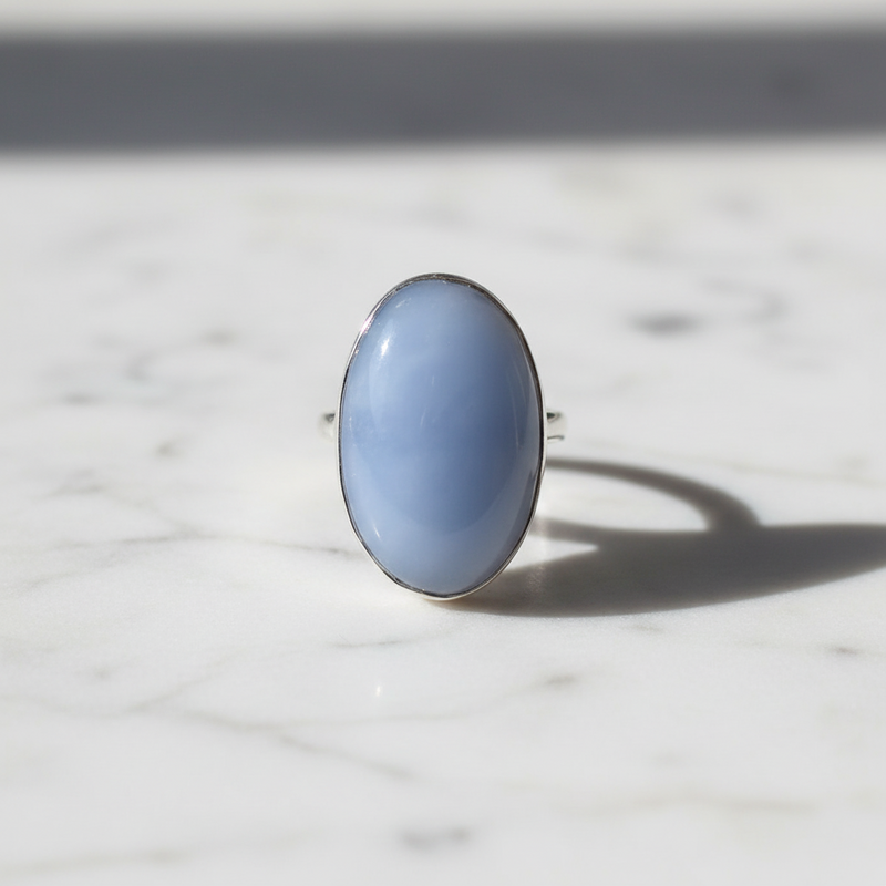 Blue ring with a silver band on a marble surface