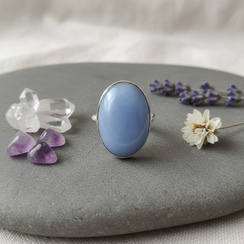 Blue stone ring on a gray surface with crystals and flowers