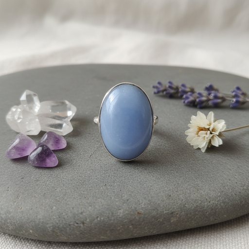 Blue stone ring on a gray surface with crystals and flowers