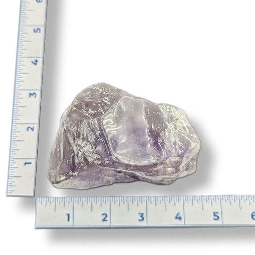 Purple stone next to a ruler on a white background