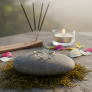 Silver rings on a stone with incense sticks and a candle in the background