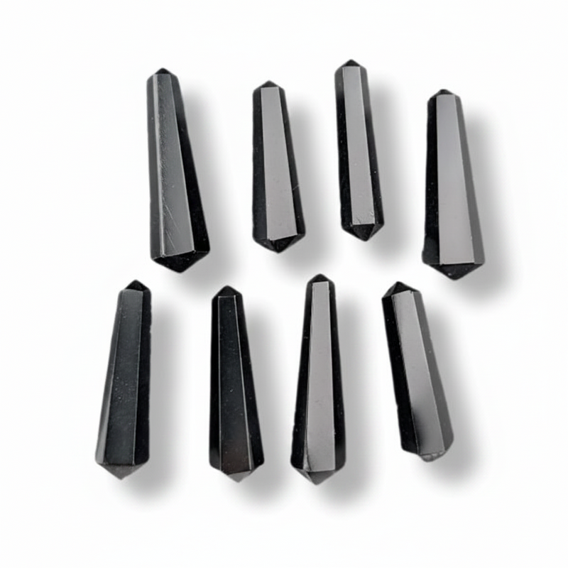 Eight faceted black crystal points arranged in two rows on a white background, each casting a soft shadow.