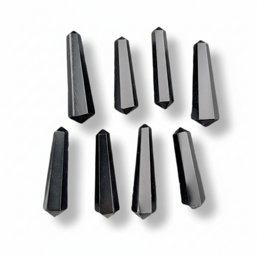 Eight faceted black crystal points arranged in two rows on a white background, each casting a soft shadow.
