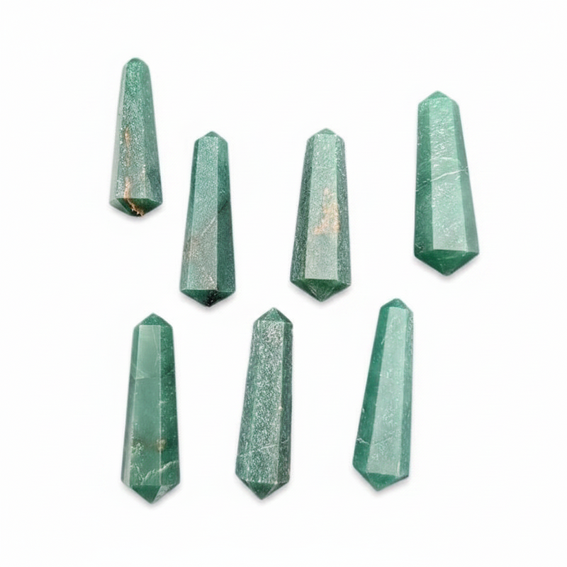 Seven faceted green crystal points arranged on a plain white background.