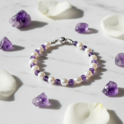 Bracelet with purple and white beads on a marble surface with amethyst stones.
