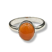 Silver ring with a large orange stone on a white background
