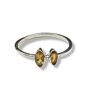 Silver ring with two yellow gemstones on a white background