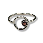 Silver ring with a central gemstone on a white background