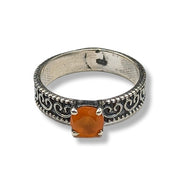 Silver ring with an orange gemstone on a white background